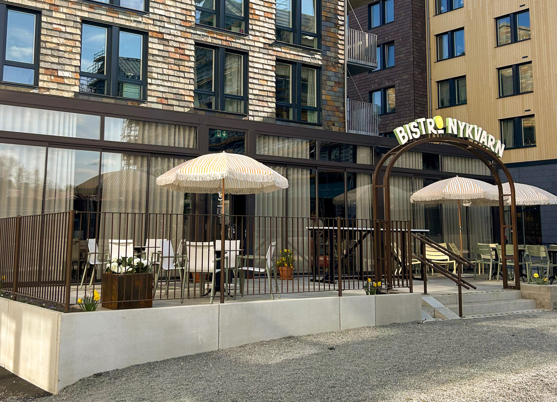Monterad skyltbåge och uteservering med parasoller på plats hos Bistro Nykvarn