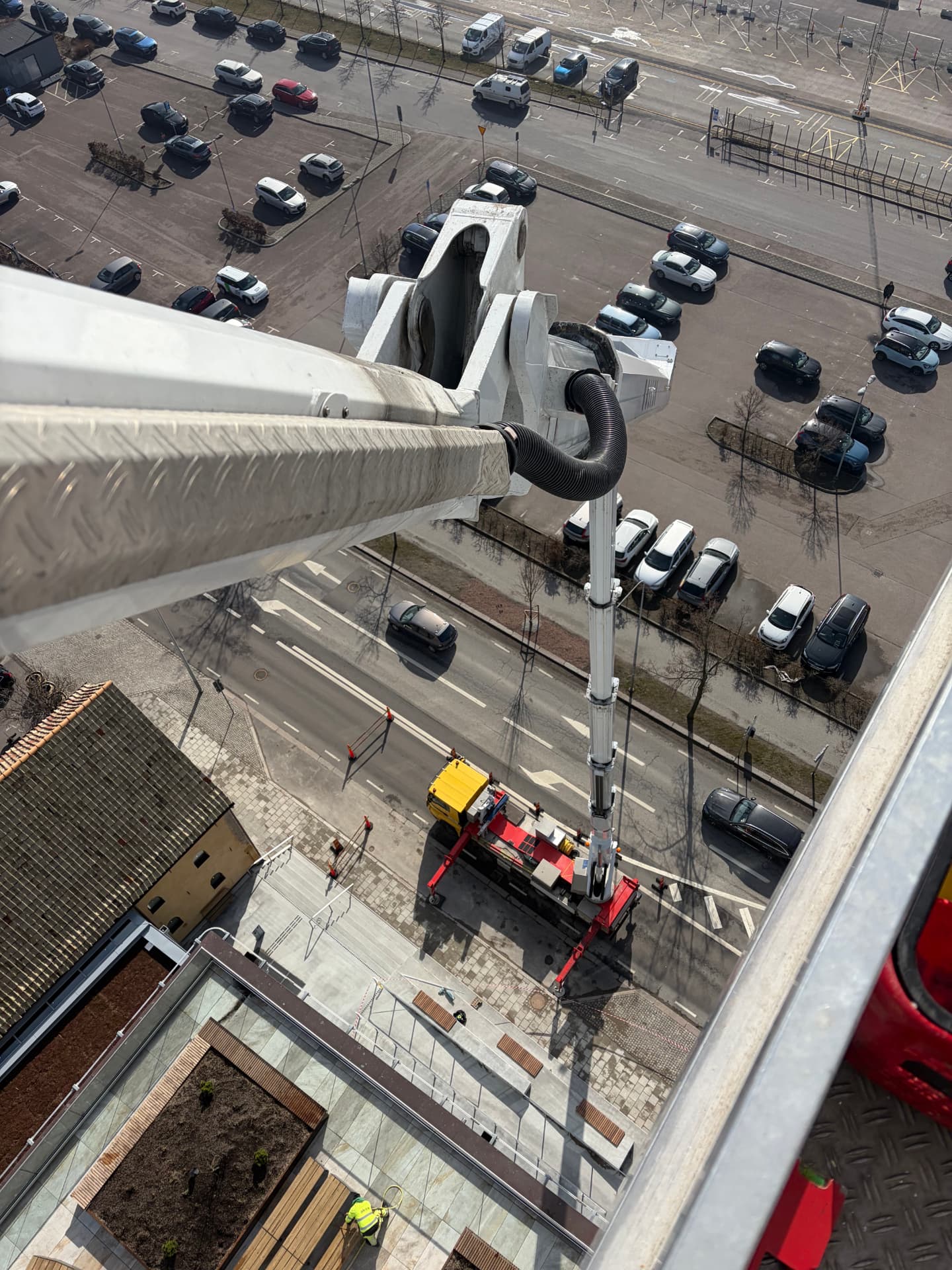 Vy från skyliftens korg högt över gata och parkering under pågående skyltmontage