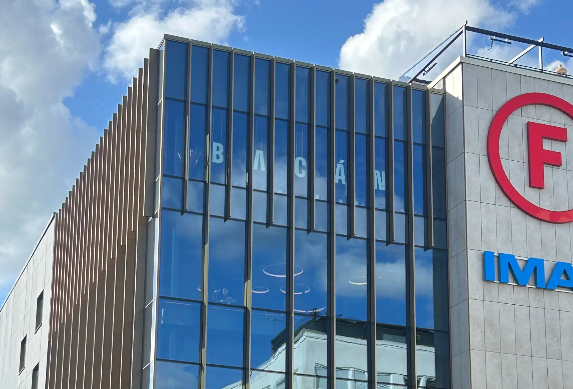 Monterade fasadbokstäver för Bacán på glasfasaden i dagsljus