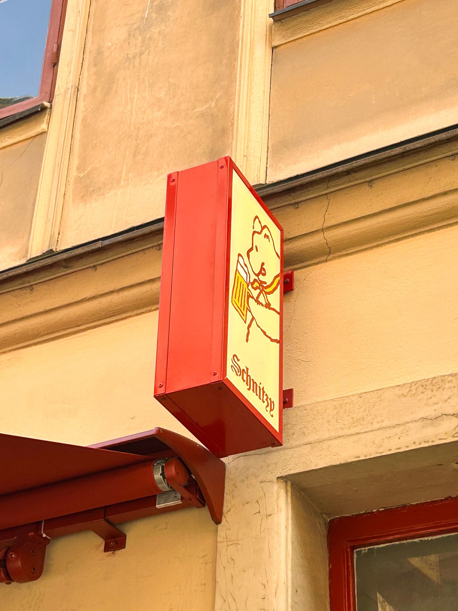 Schnitzys entré i Gamla Stan i kvällsljus med belyst skyltning